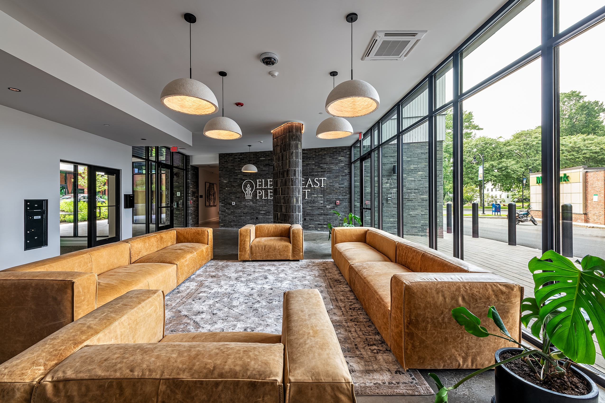 Resident lounge at Eleven East Pleasant in Amherst, Massachusetts, with sofas, tables, and floor-to-ceiling windows.