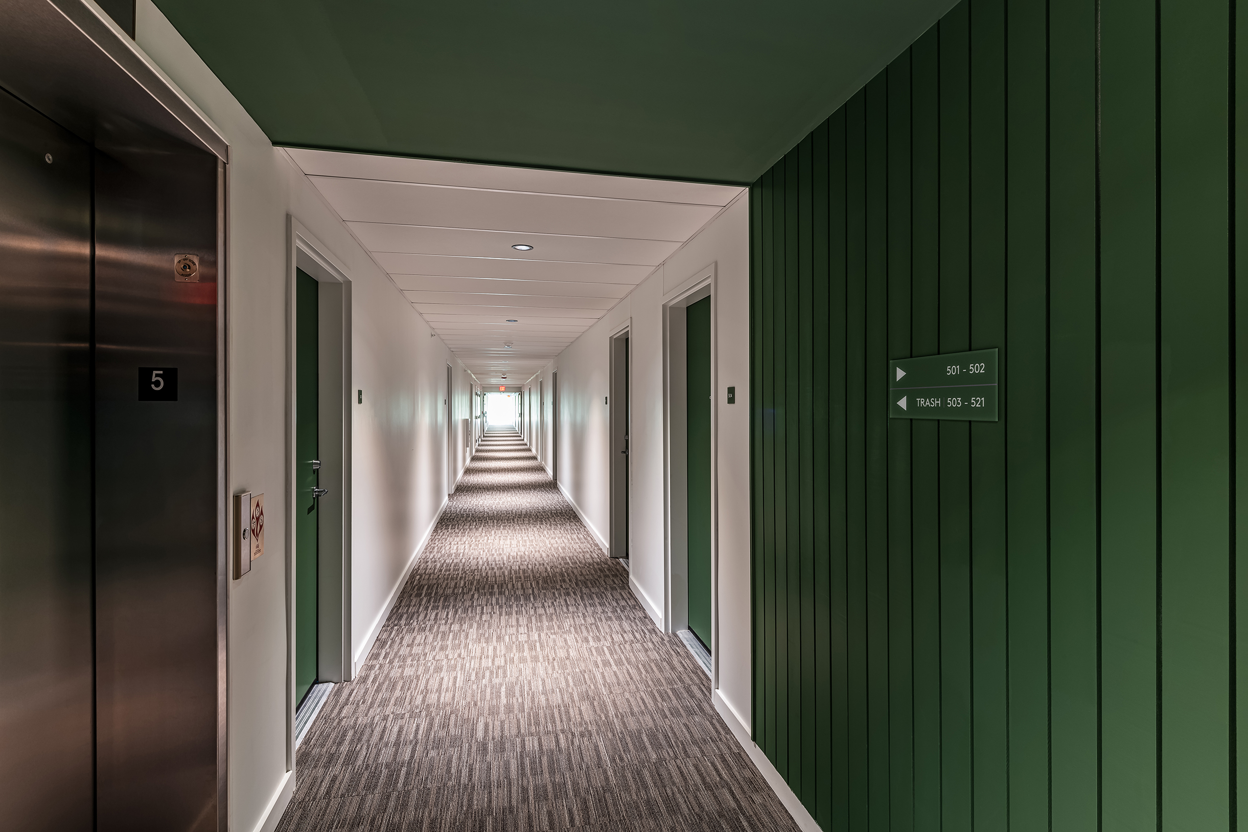 Residential corridor at Eleven East Pleasant in Amherst, Massachusetts, with apartment entrances along a central hallway.