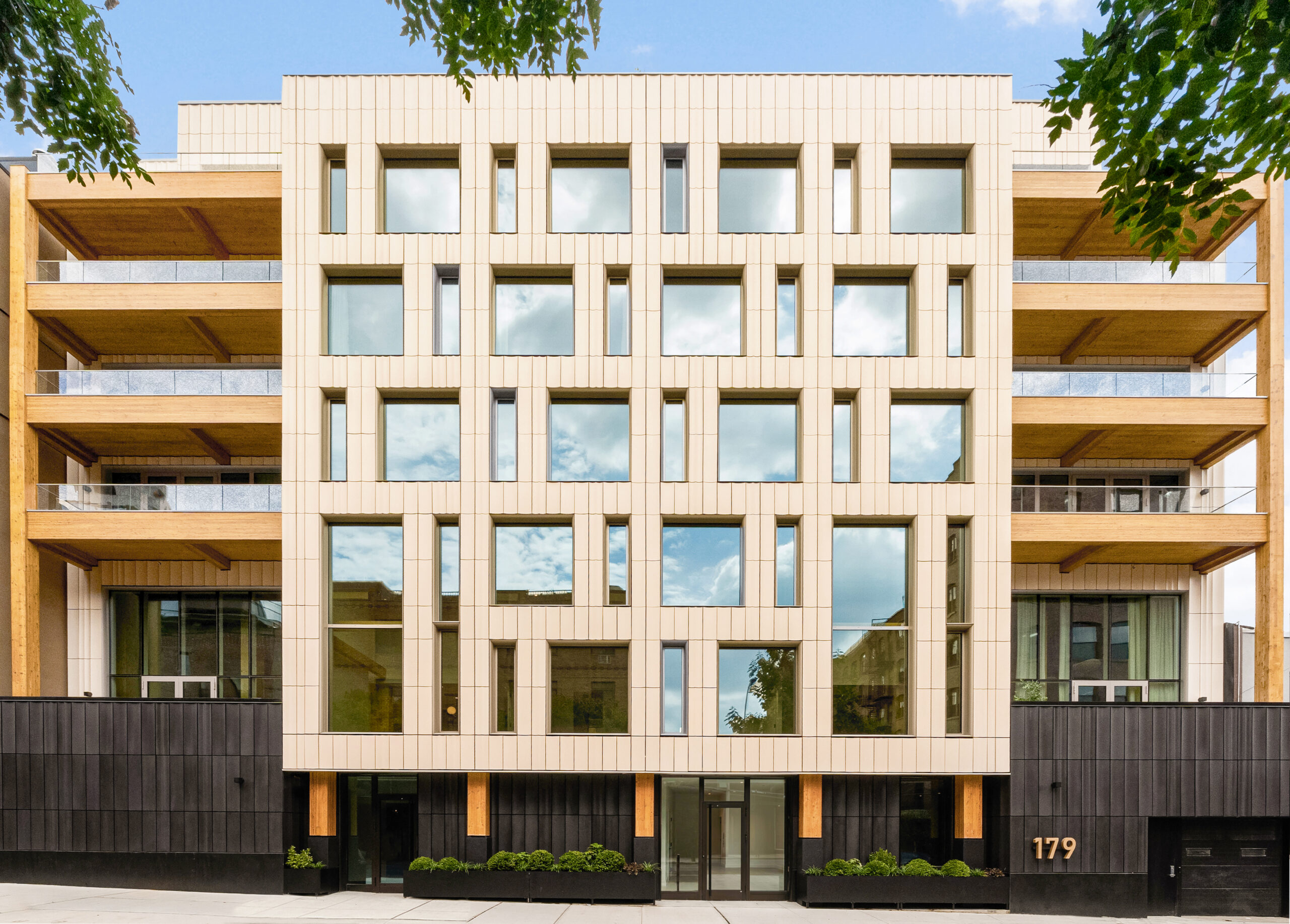 Front exterior of Timberburg in New York City, featuring terra cotta cladding, large windows, and exposed timber balconies.