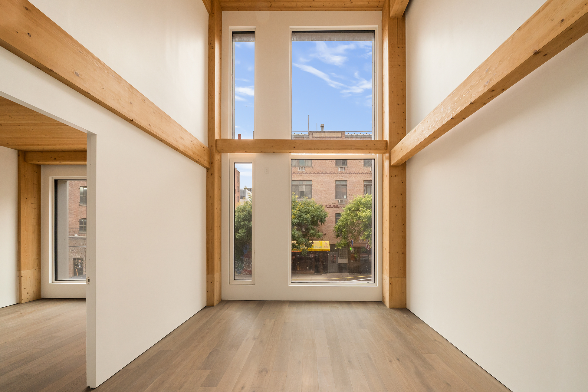 Interior at Timberburg in New York City, with exposed glulam beams and columns framing large windows.