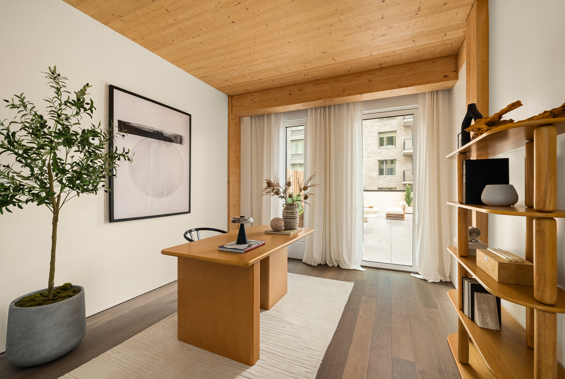 Home office at Timberburg in New York City, with exposed mass timber ceilings, wood shelving, and glass doors opening to a terrace.
